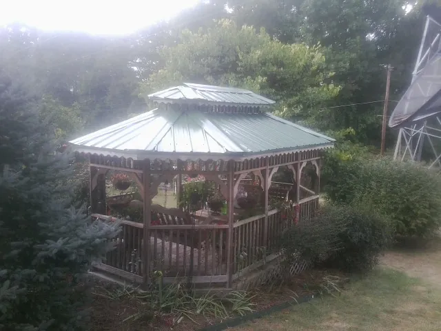 Green metal roof on a backyard gazebo surrounded by garden beds in Argyle